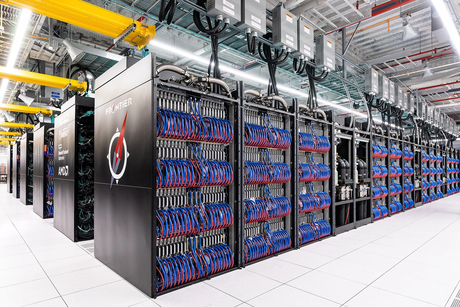 Rows of Frontier computing cabinets with exposed red and blue cables at Oak Ridge National Laboratory.