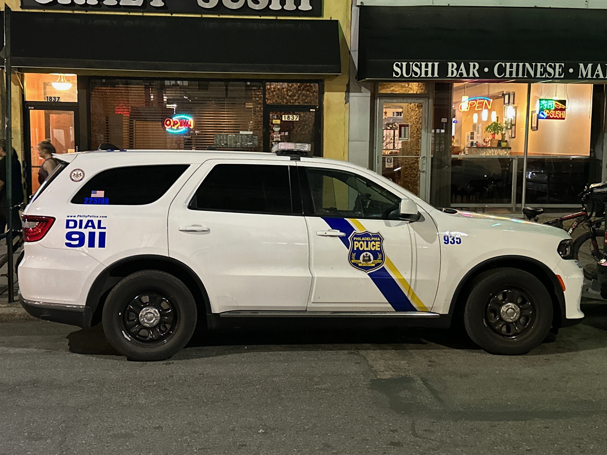 A white Philadelphia Police sport utility vehicle parked on a city street at night.