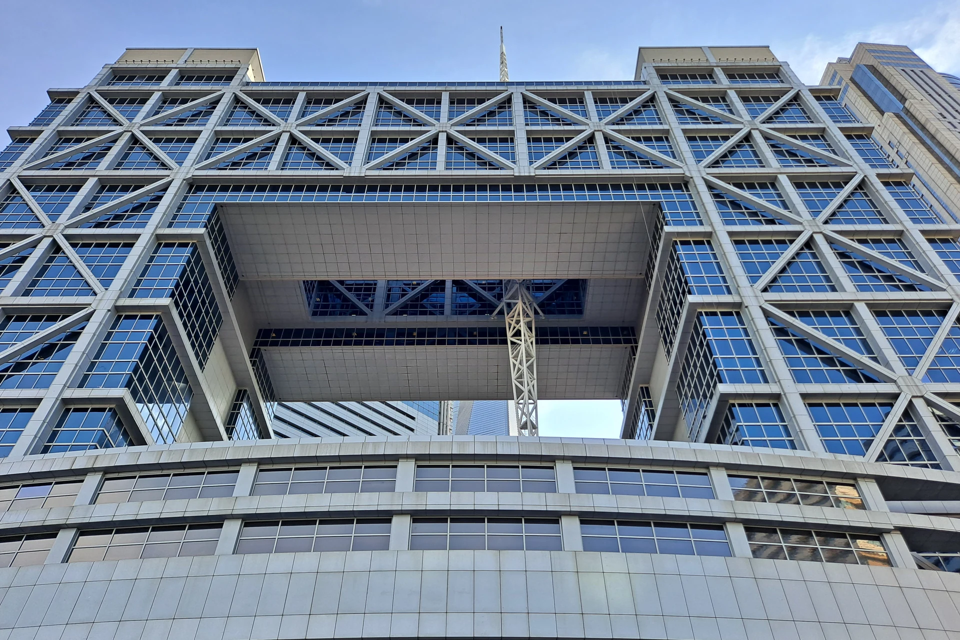 An upward view of the glass facade and steel cross-bracing of the Shanghai Stock Exchange building.