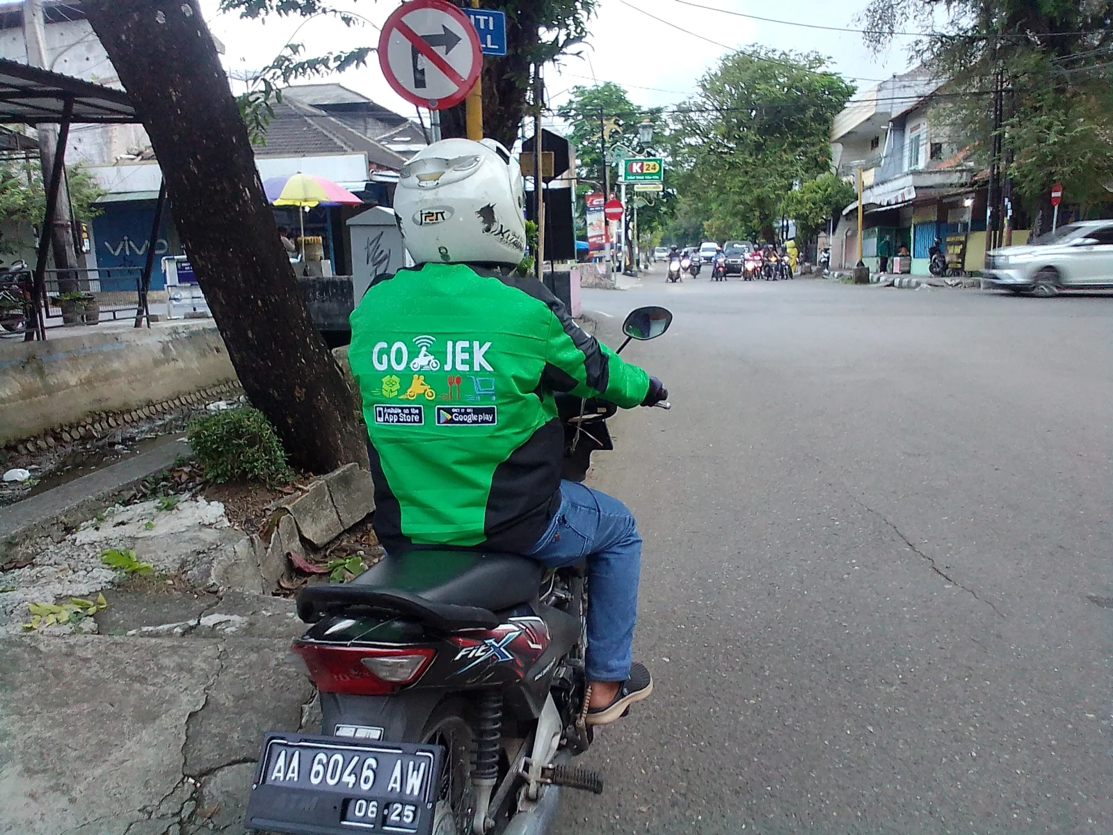 A motorcyclist wearing a green Gojek jacket on a street in Kebumen
