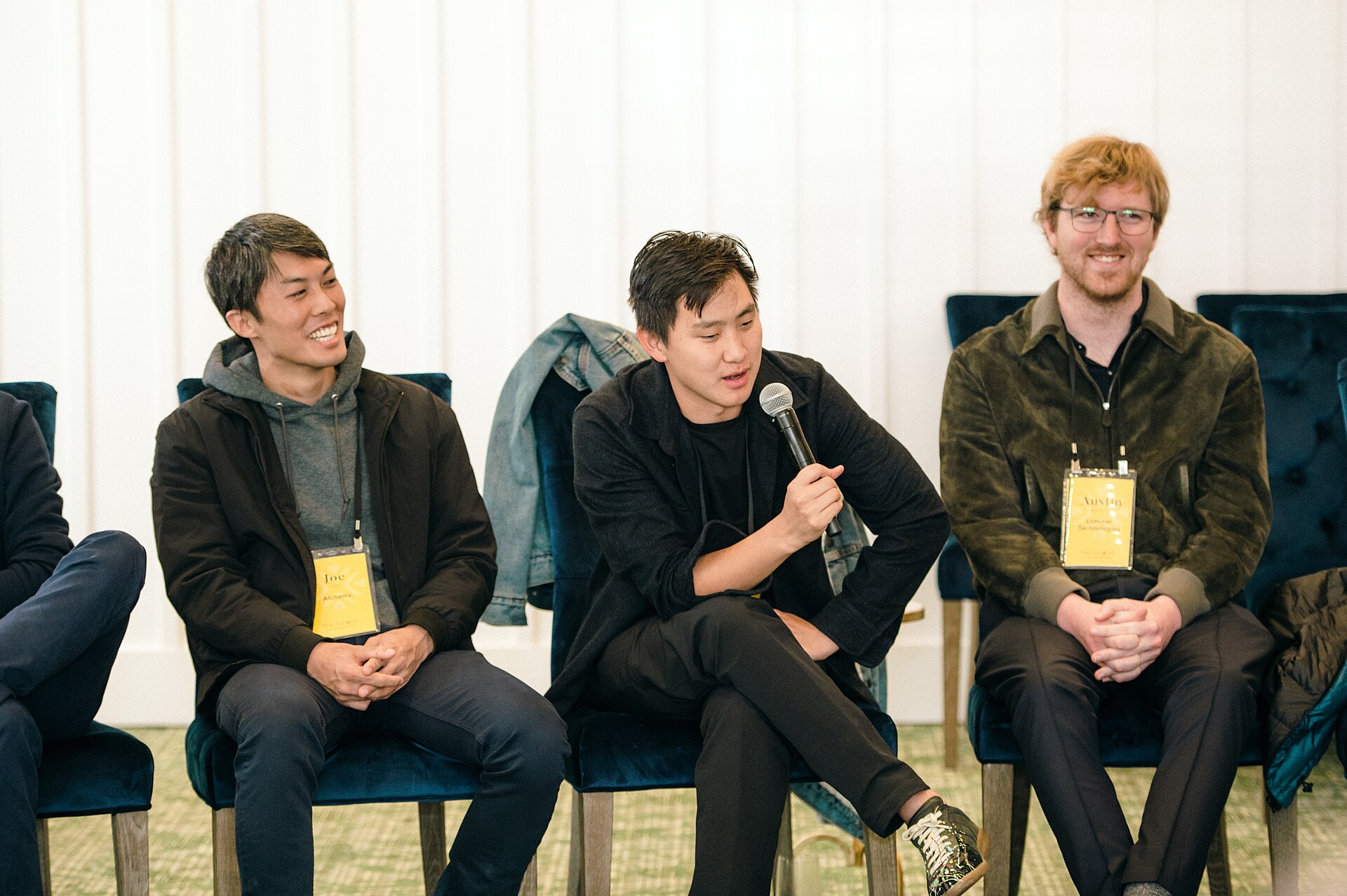 Alexandr Wang sits between two attendees and speaks into a microphone at Village Global’s Grove event.