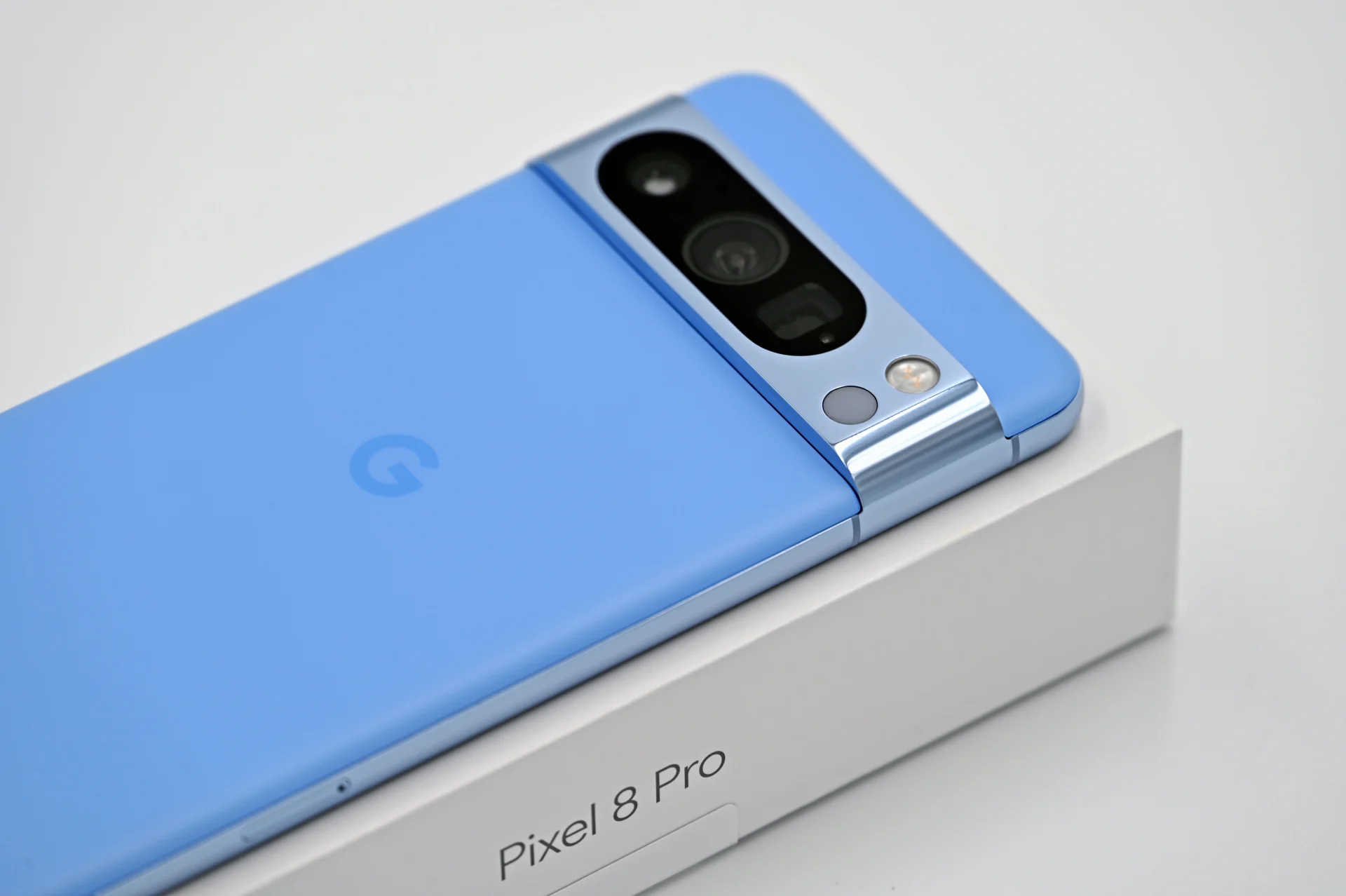 A blue Google Pixel 8 Pro smartphone resting on its retail box.