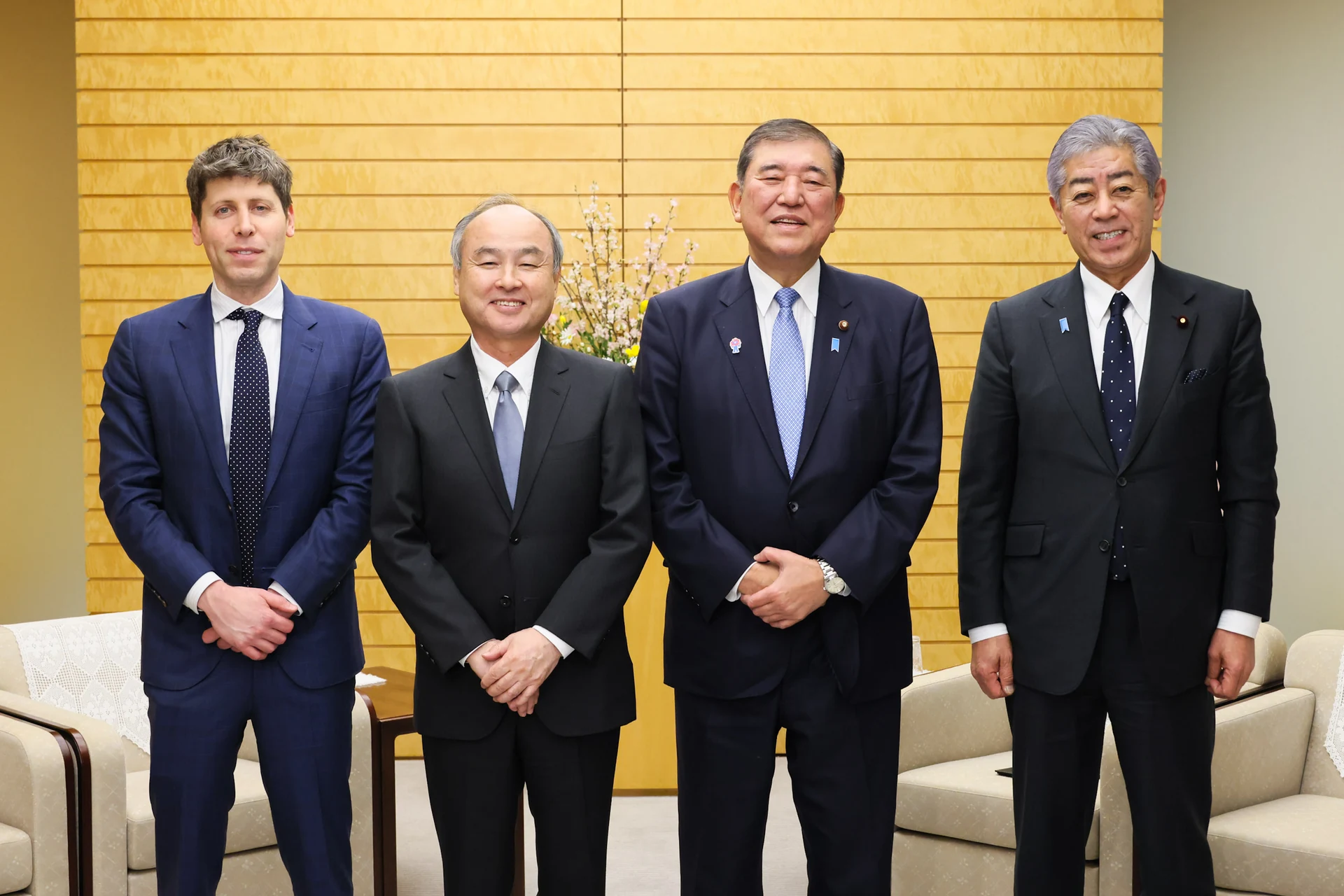 Sam Altman stands with Masayoshi Son, Shigeru Ishiba and Takeshi Iwaya in front of a gold wall.
