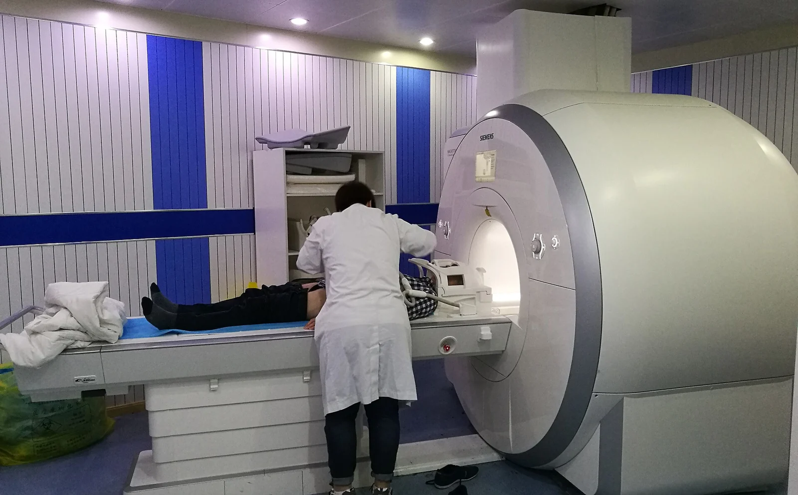 A medical worker positions a patient in a Siemens MRI scanner.