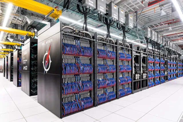Rows of Frontier computing cabinets with exposed red and blue cables at Oak Ridge National Laboratory.
