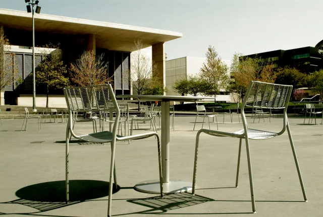 Metal chairs in Rosa Parks Circle with Grand Rapids Art Museum behind them.