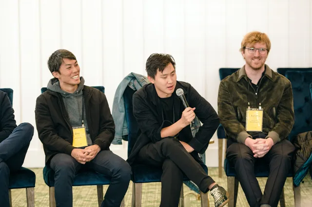 Alexandr Wang sits between two attendees and speaks into a microphone at Village Global’s Grove event.