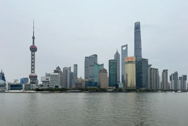 Shanghai towers rise across the Huangpu River under a pale sky.