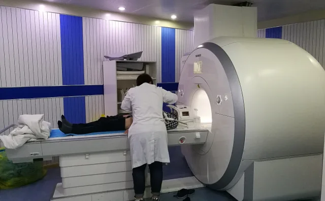 A medical worker positions a patient in a Siemens MRI scanner.